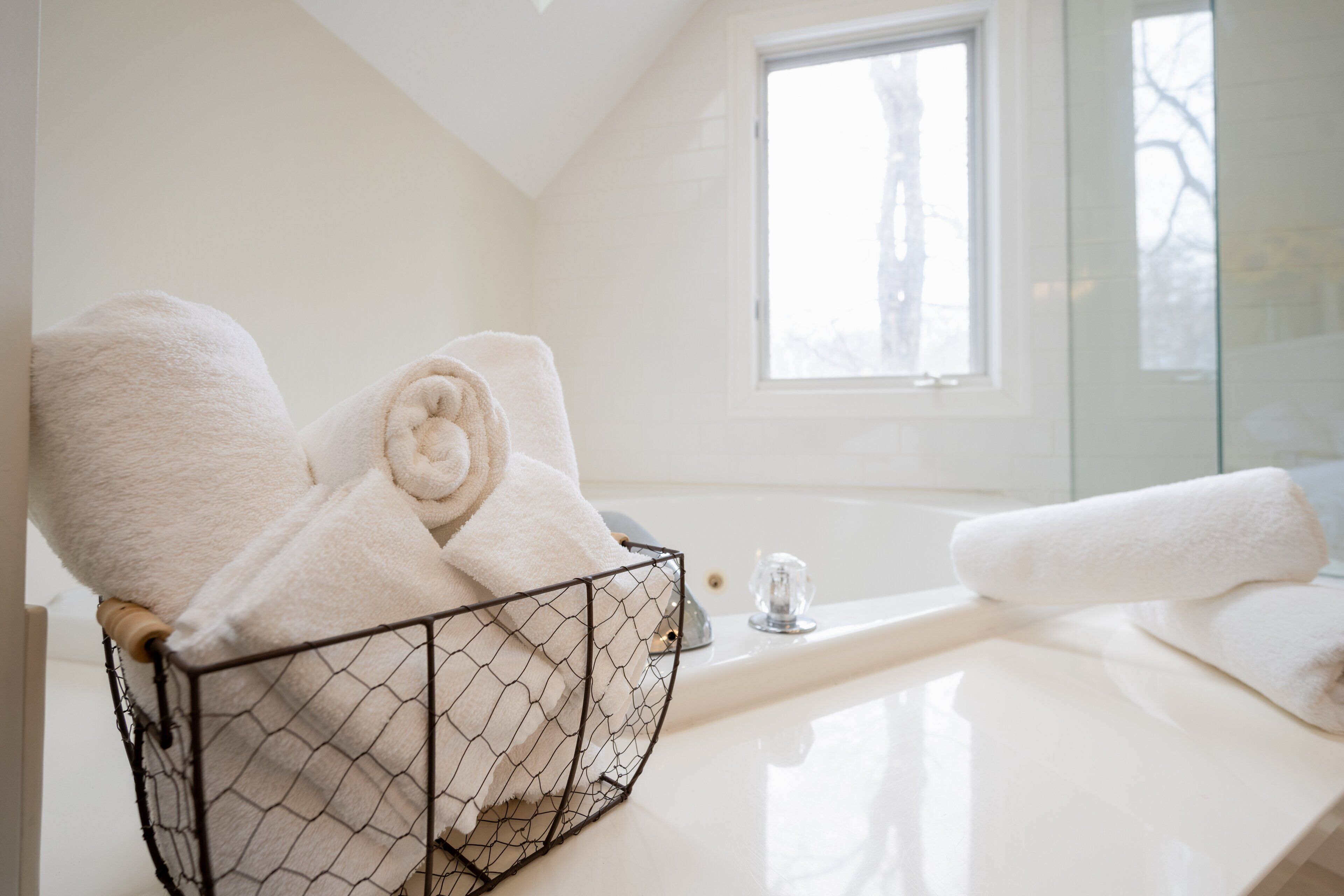Ein Badezimmer mit einer weißen Badewanne, einem Fenster und einem Handtuchhalter mit gefalteten Handtüchern.