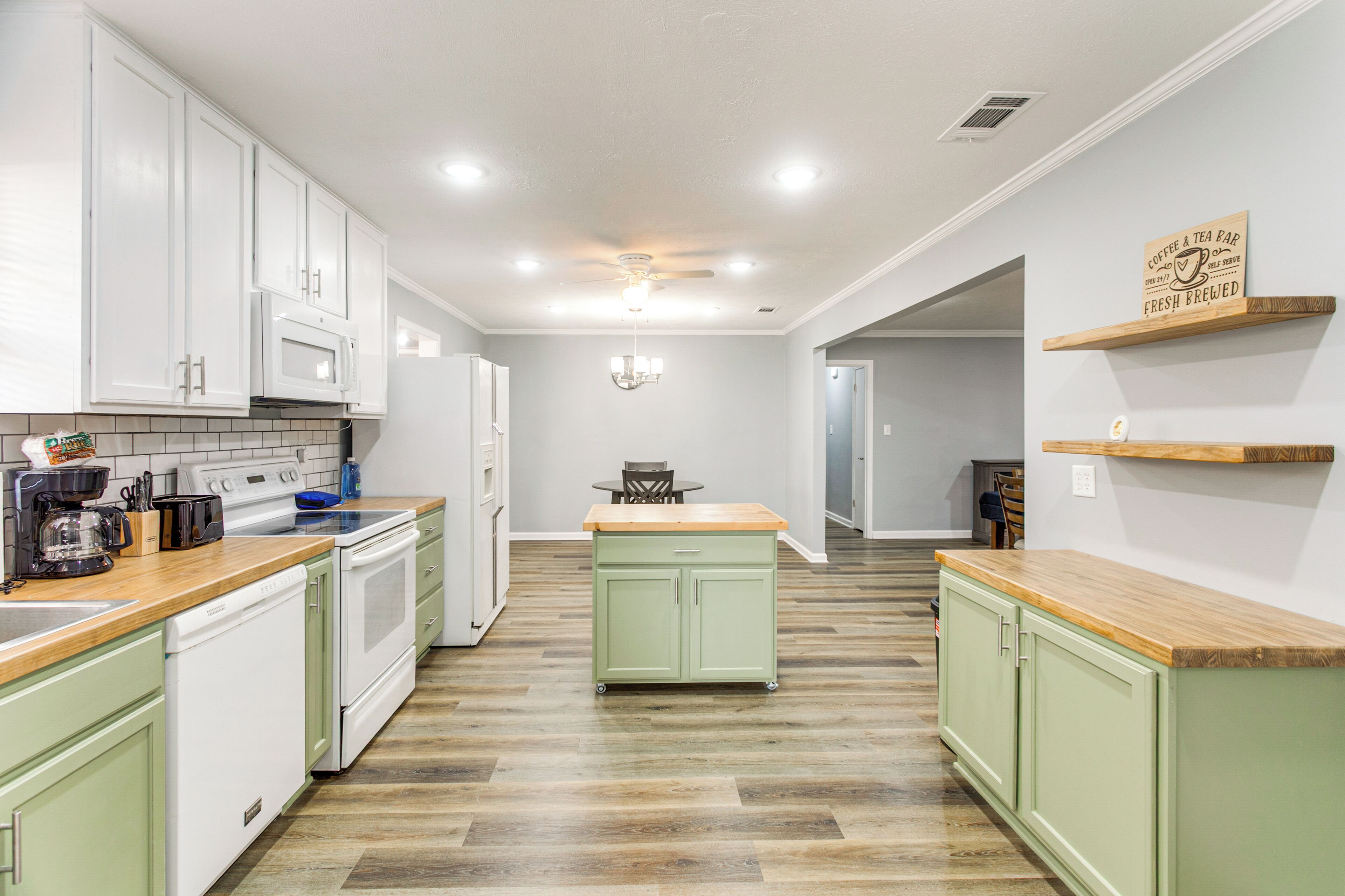 A kitchen with white cabinets, a wooden countertop, and a green island.