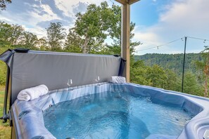 A hot tub with a canopy, two glasses, and a towel, set against a backdrop of trees and a clear sky. - Luxury Cabin, Mountain Views, Hot Tub, EV Charger (Ellijay)