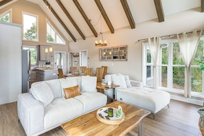A spacious living area with a large sofa, a coffee table, and a dining table set for four. - Luxury Cabin, Mountain Views, Hot Tub, EV Charger (Ellijay)