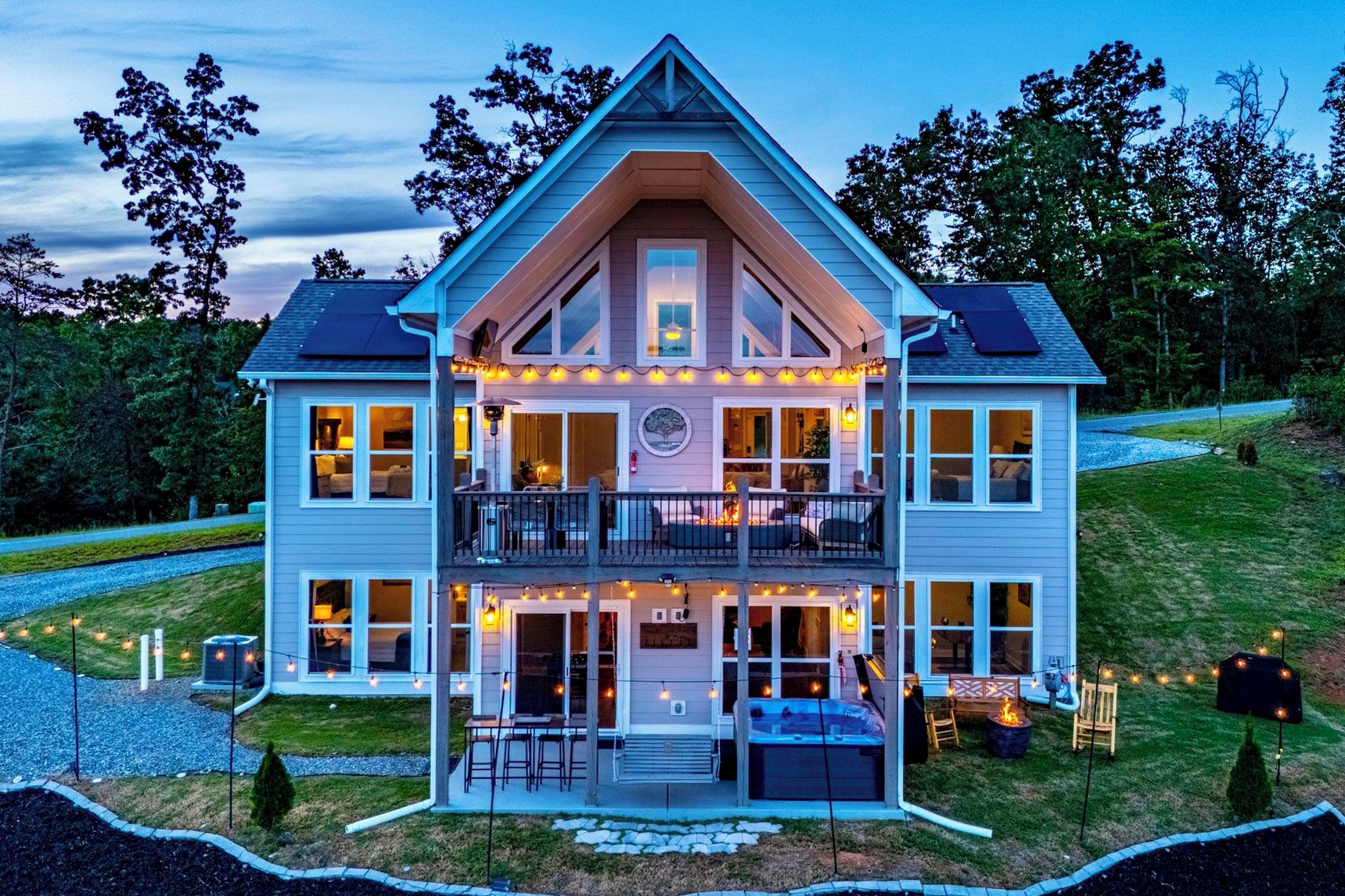 A two-story house with a balcony, outdoor seating, and a hot tub.