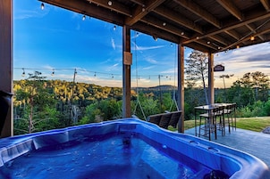 Una vasca idromassaggio sotto un gazebo in legno con vista su un paesaggio boschivo.
