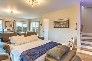 A hotel room with a large bed, a desk, a chair, a window, and a painting on the wall. - Luxury Cabin, Mountain Views, Hot Tub, EV Charger (Ellijay)