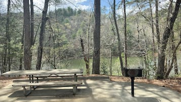 Una mesa de picnic en un área boscosa con un buzón.