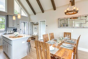 A spacious kitchen with a large island, wooden dining table, and a chandelier. - Luxury Cabin, Mountain Views, Hot Tub, EV Charger (Ellijay)