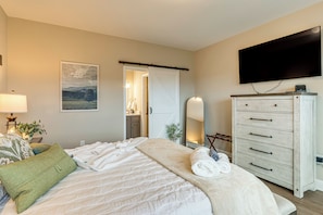 A hotel room with a bed, a dresser, a television, and a painting on the wall. - Luxury Cabin, Mountain Views, Hot Tub, EV Charger (Ellijay)