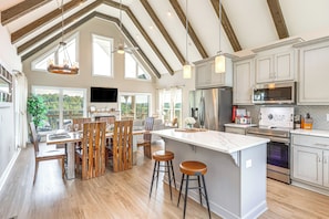 A spacious kitchen with high ceilings, wooden beams, a large island, and modern appliances. - Luxury Cabin, Mountain Views, Hot Tub, EV Charger (Ellijay)