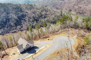 A house with a large driveway and a pond in the background. - Sol & Luna: Luxury Cabin, Mountain Views, Hot Tub (Ellijay)
