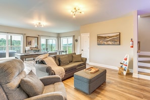 A spacious living room with a sofa, ottoman, and a pool table. There is a painting on the wall and a fire extinguisher mounted on the wall. - Luxury Cabin, Mountain Views, Hot Tub, EV Charger (Ellijay)