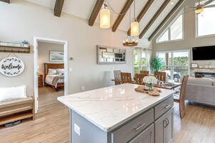 Cucina spaziosa con piano di lavoro in marmo, travi al soffitto in legno e illuminazione a sospensione.