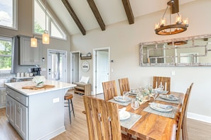A spacious kitchen with a large island, wooden dining table, and a chandelier. - Luxury Cabin, Mountain Views, Hot Tub, EV Charger (Ellijay)