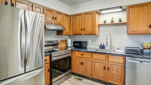 Una cocina moderna con armarios de madera, electrodomésticos de acero inoxidable y un microondas.