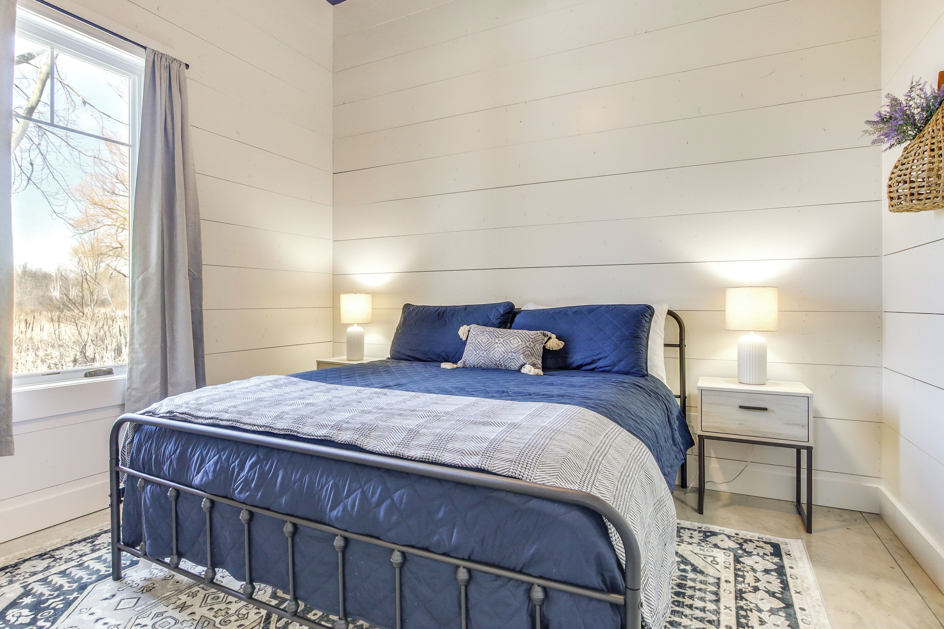 A bedroom with a bed, bedside lamps, a window, and a nightstand.