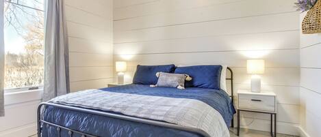 A bedroom with a bed, bedside lamps, a window, and a nightstand.
