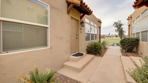 A building with a beige exterior, large windows, a door with a small porch, and a pathway leading to the entrance. - Walk to Colorado River: Needles Gem w/ Pool Access (Needles)