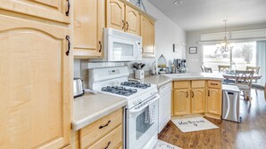 A kitchen with wooden cabinets, a microwave, stove, and dishwasher. - Walk to Colorado River: Needles Gem w/ Pool Access (Needles)