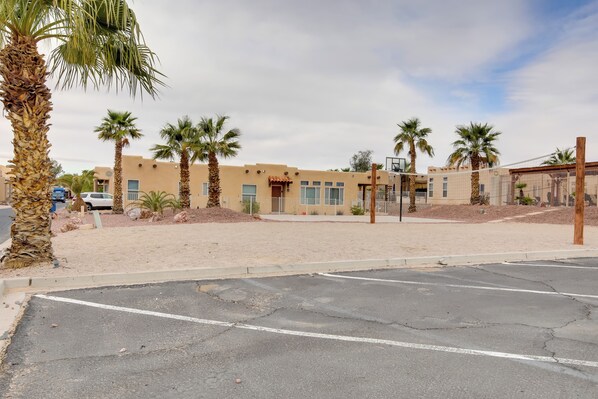 A parking lot with palm trees and a building with a basketball hoop.