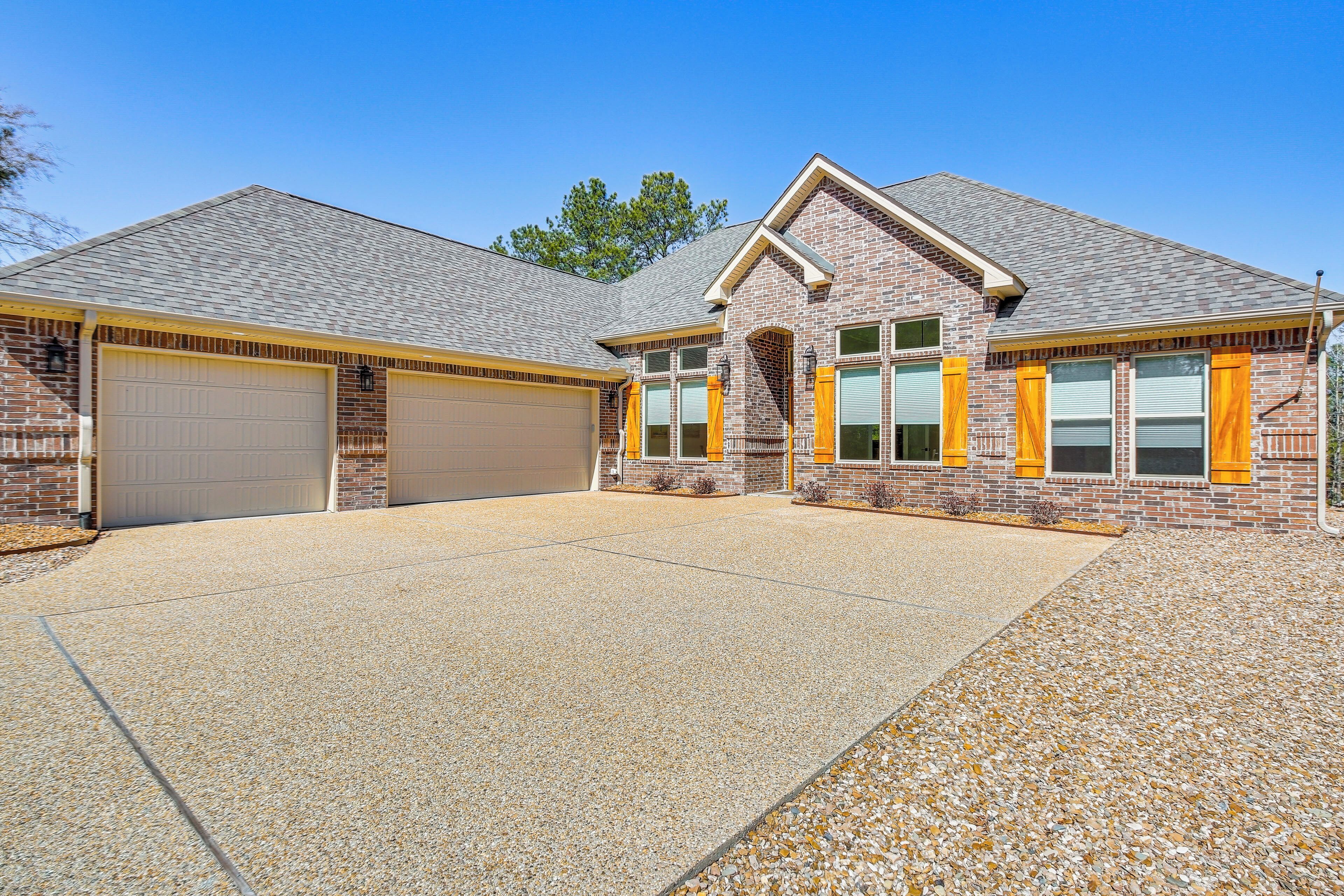 A two-story house with a garage, a covered driveway, and a brick exterior.