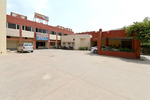 A building with a sign for 'Magpie Tourist Complex' and a 'Family Restaurant'. There are parked cars and motorcycles in front. - Magpie Tourist Resort (Faridabad)