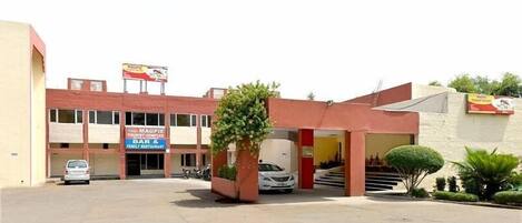 A building with a sign for a bar and restaurant. There is a parking area with a few cars.
