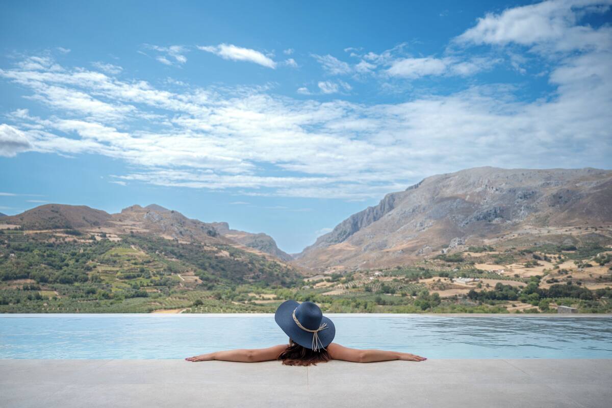 A person relaxing by a pool with a mountainous landscape in the background.