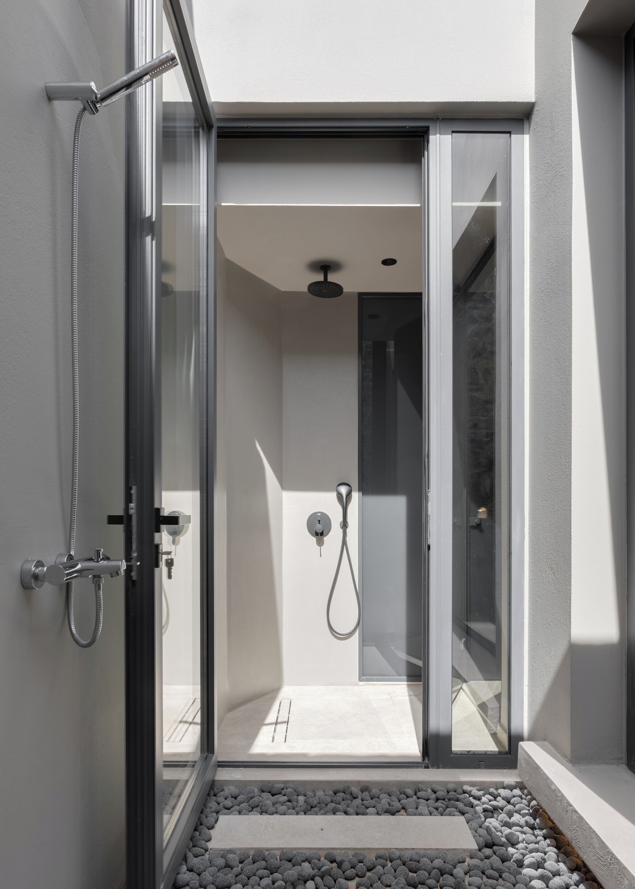 A modern shower area with a glass door, a handheld showerhead, and a control panel.