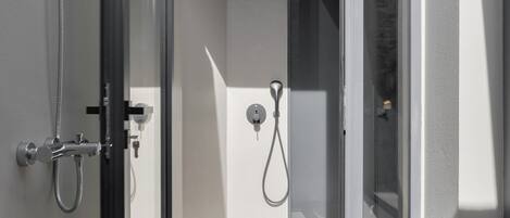 A modern shower area with a glass door, a handheld showerhead, and a control panel.