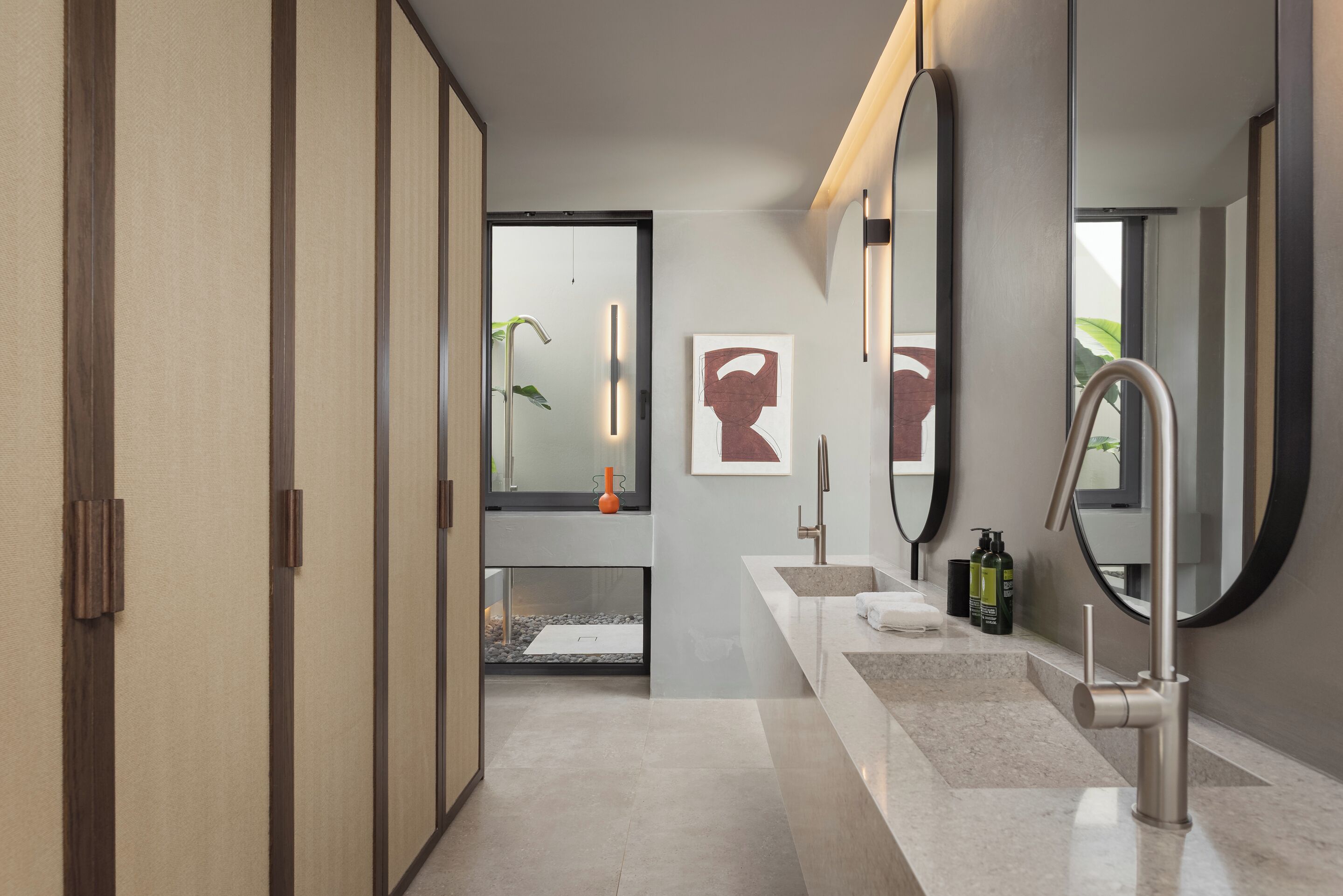 Une salle de bain moderne dotée d’une douche à l’italienne, d’un grand miroir et d’un meuble-lavabo avec un évier et un plan de travail.