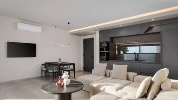 A modern living room with a sectional sofa, a round coffee table, and a dining area with chairs.