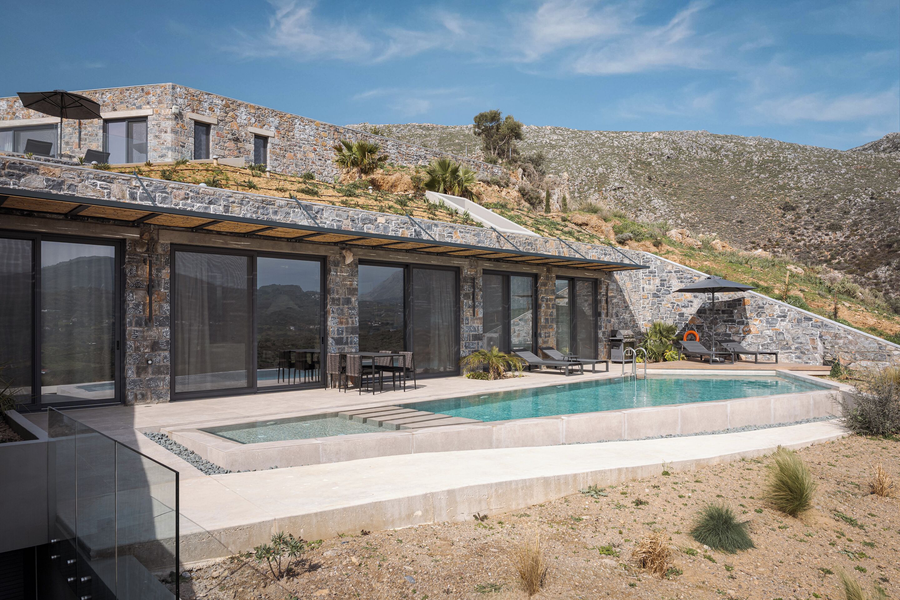 A modern house with a pool, stone exterior, and large windows.