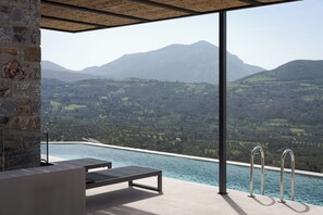 Relax by the modern pool, surrounded by a mountainous landscape and a sturdy stone wall.