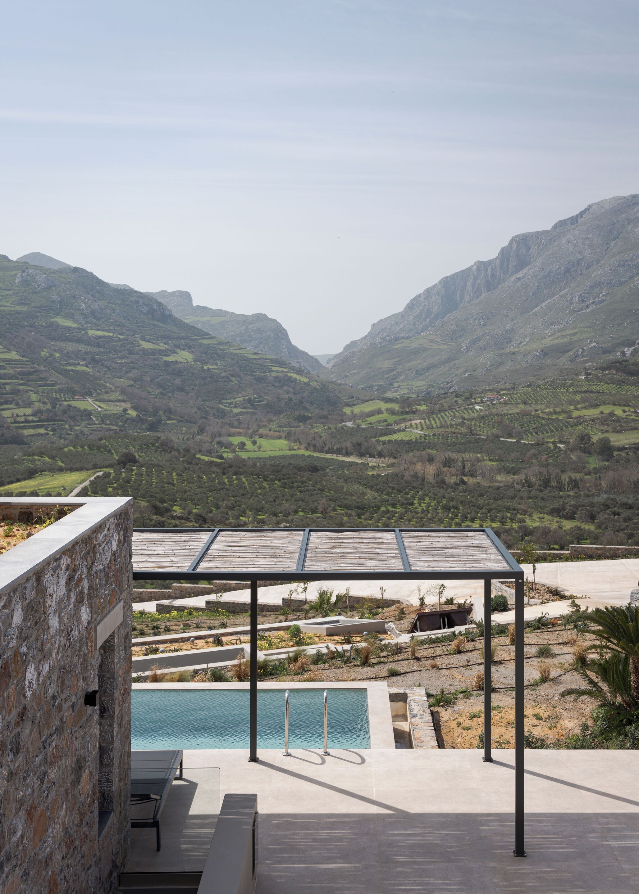 Un espace piscine agrémenté d’une pergola offrant une vue sur un paysage montagneux.