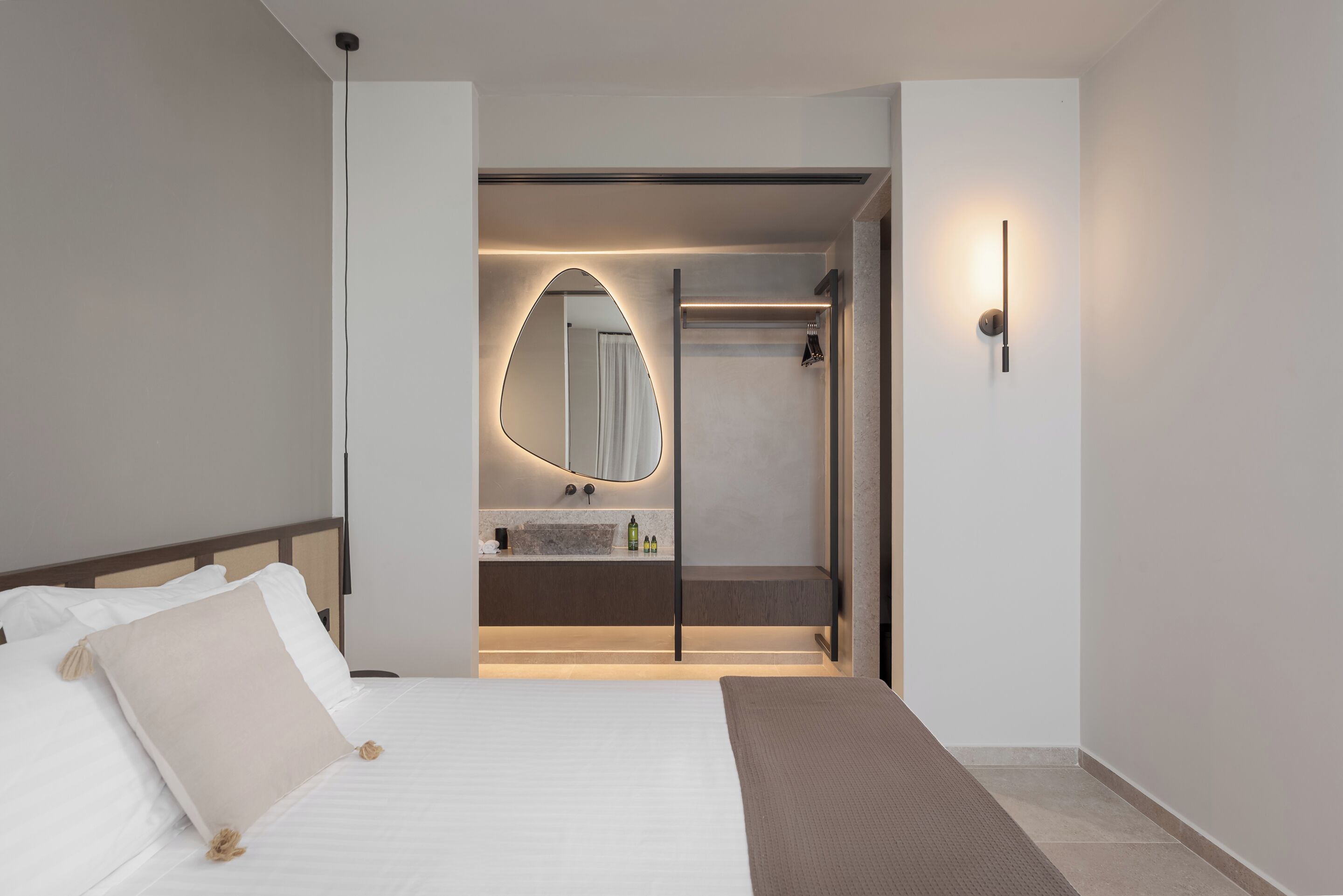 A modern hotel room with a large bed, a bathroom with a vanity, and a shower.