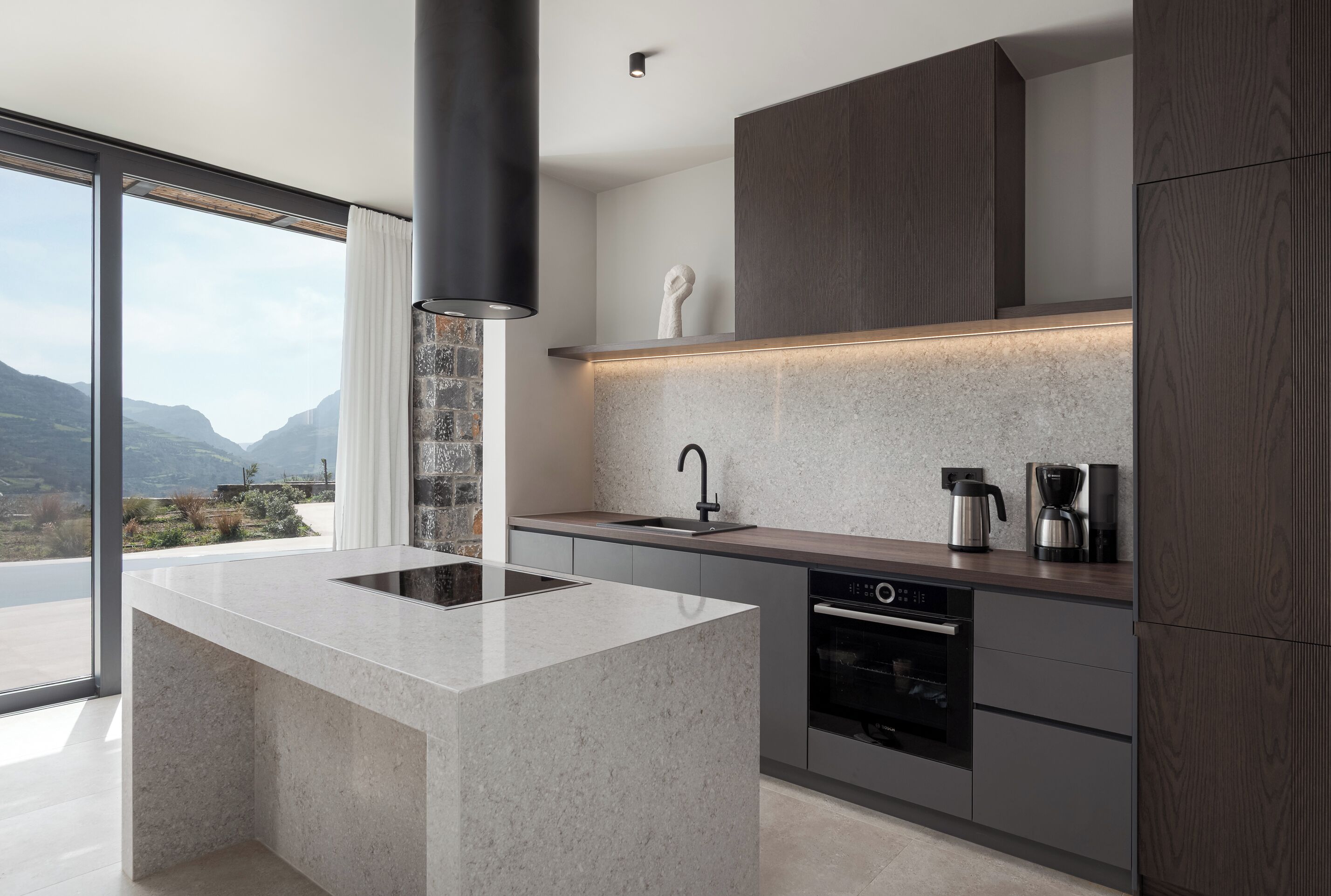 Una cucina moderna con isola centrale, elettrodomestici integrati e vista sull'esterno.