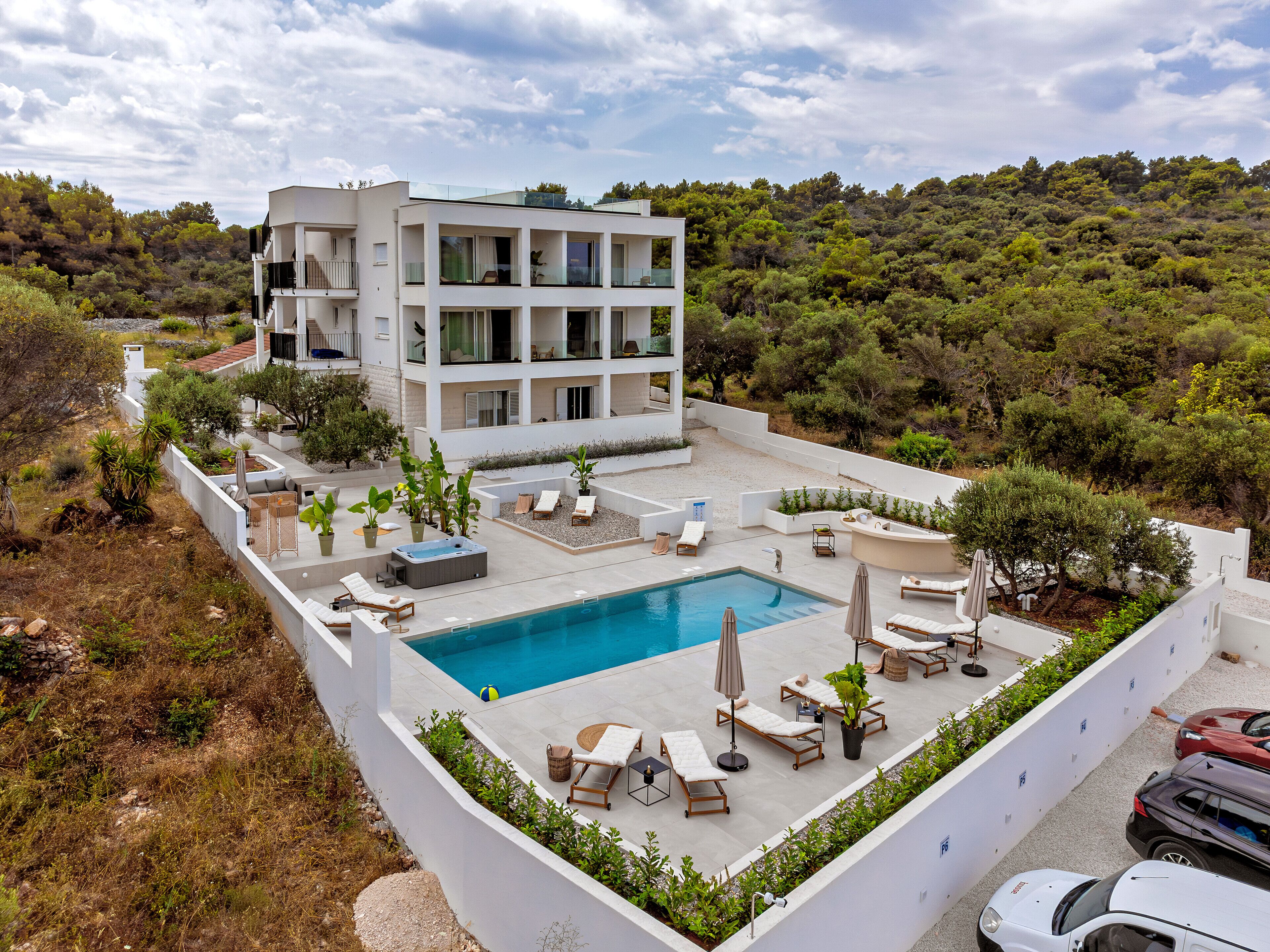 Un edificio moderno con piscina, lettini e giardino.