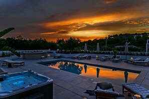 A rooftop pool area with lounge chairs and a hot tub, surrounded by greenery and a sunset view. - Villa del Sogno (Okrug Gornji)