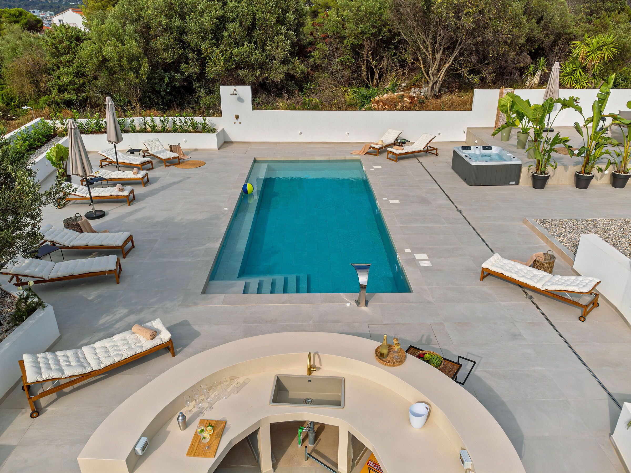 Un espace piscine aménagé sur le toit, avec des chaises longues, un jacuzzi et un bar.