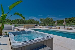 En säsongsöppen utomhuspool, parasoller och solstolar