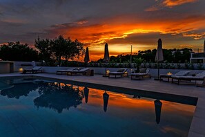 A rooftop pool area with lounge chairs and umbrellas, reflecting a sunset sky. - Villa del Sogno (Okrug Gornji)