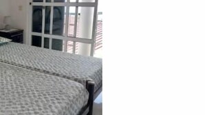 Une chambre à coucher comprenant un lit, une table de chevet et une porte-fenêtre coulissante donnant sur un balcon.