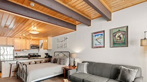 A cozy room with a bed, a sofa, a wooden table, and a kitchenette. - Large Studio; Excellent Location; Hot Tubs (Breckenridge)