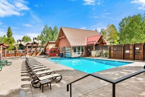 A swimming pool with lounge chairs and a building with a red roof.