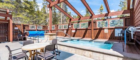 A wooden deck with a pool, outdoor seating, and a covered area.