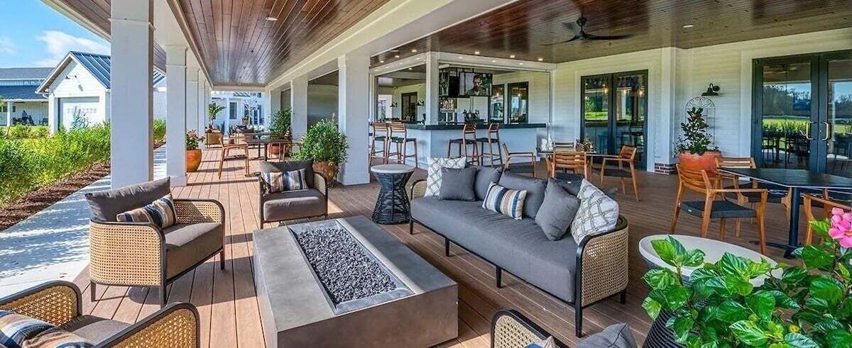A covered outdoor seating area with sofas, chairs, and a bar.