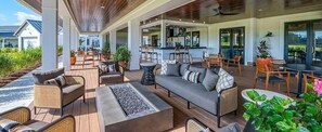 Un espace extérieur aménagé, abrité et doté de canapés, de fauteuils et d’un bar.