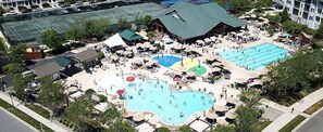 Ein Resort mit mehreren Swimmingpools, einem überdachten Bereich mit Liegestühlen und einem Parkplatz.