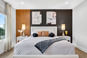 Ein modernes Schlafzimmer mit einem großen Bett, zwei Nachttischen und Blick ins Freie.