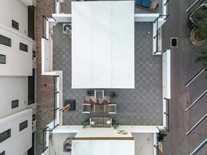 An aerial view of a rooftop terrace with a large white banner, a seating area with a sofa and chairs, and a small table. - Skyview Escape | Rooftop Townhouse Near Clearwater (Largo)