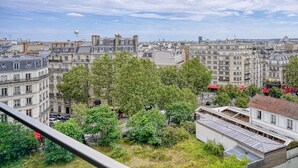 Eine Stadtansicht mit einer Mischung aus Wohngebäuden, darunter mehrstöckige Wohnblocks und ein historisches Haus mit einer Holzterrasse.