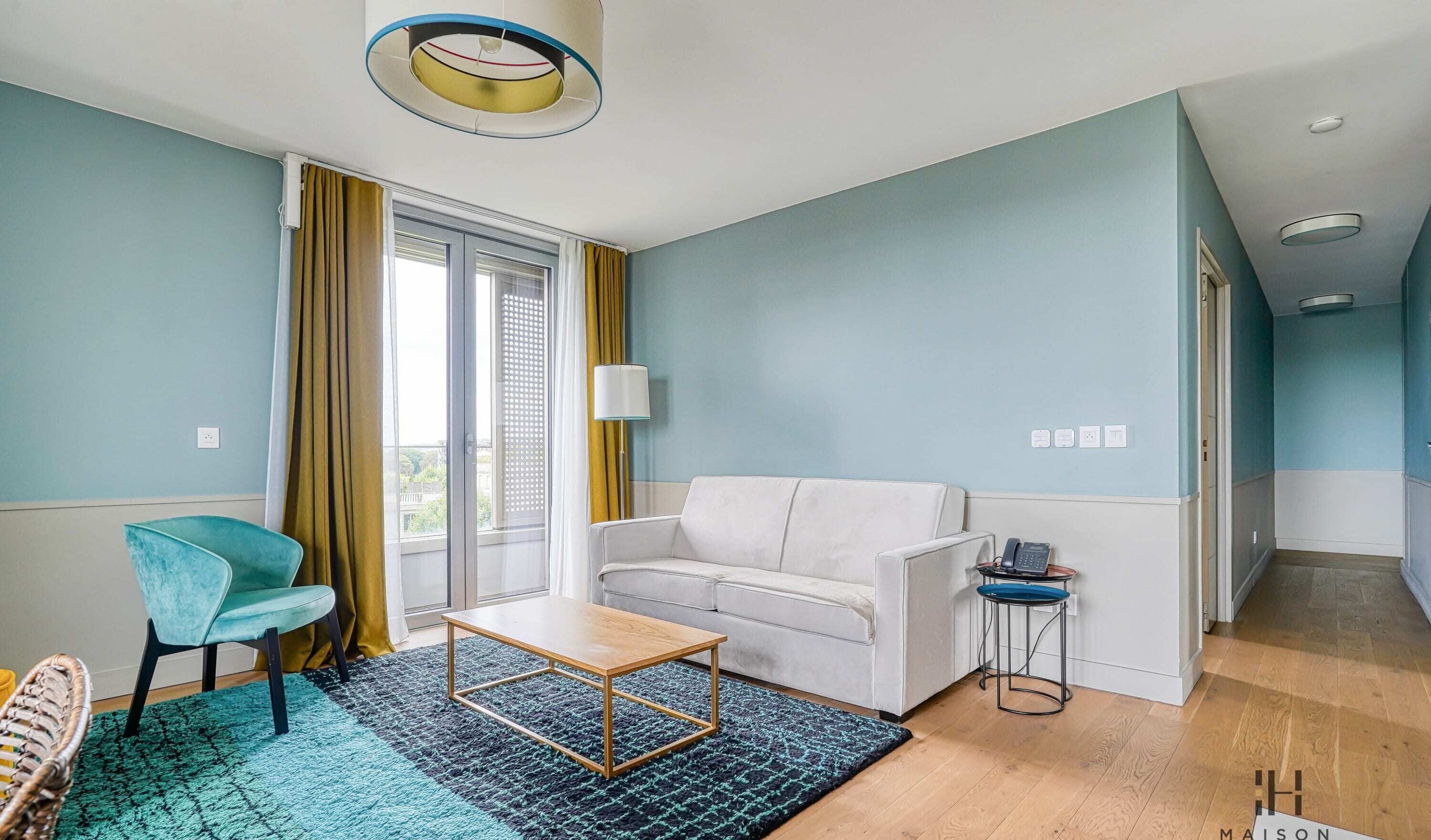 En moderne stue med en sofa, et lille bord, en stol og en lampe.